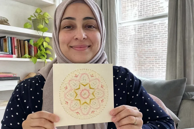 Claudia F. holding her finished mandala paper-embroidery