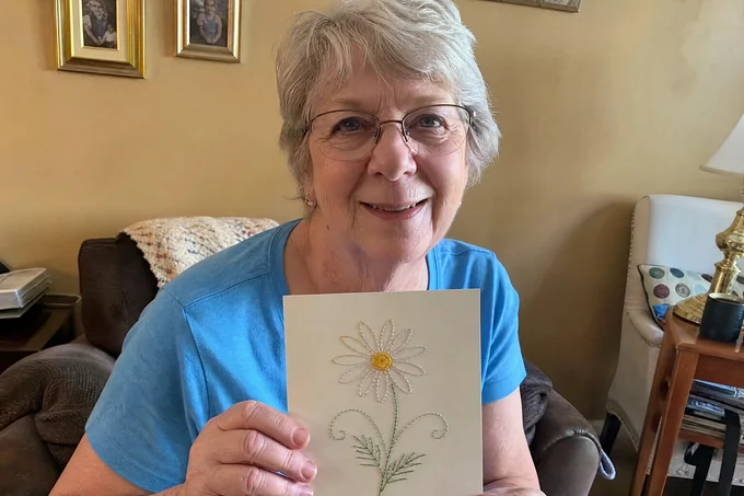 Marion S. holding her first finished paper-embroidery daisy